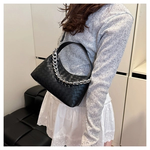Close-up of black woven leather texture and chunky silver chain on the underarm bag