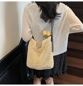Detail of hand-woven cotton shoulder bag with brown leather straps in a home setting