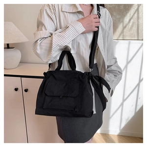 Vue détaillée du sac cabas en nylon noir avec cordon de serrage et nœuds latéraux chic
