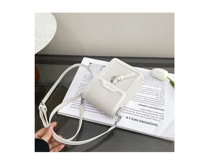 Detail of cream woven leather mini crossbody bag and adjustable strap on a magazine
