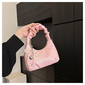 Detail of pink faux leather handbag with pleated handle and pearl bow decoration
