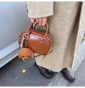 Detail of brown vintage crossbody bag with embossed logo and teddy charm decoration