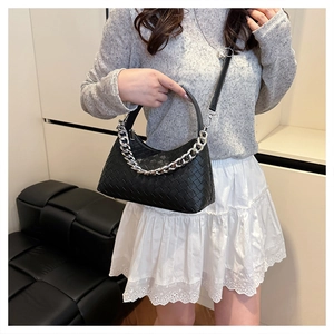 Detailed view of black woven dumpling bag with thick silver chain and leather strap