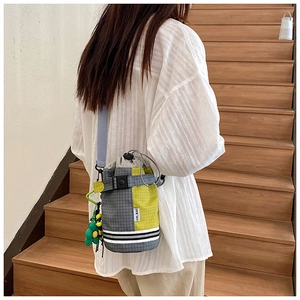 Detail of checkered cycling bucket bag with drawstring closure and floral charm
