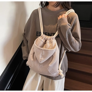 Detail of waffle-textured drawstring bucket bag with cotton rope straps and rear pocket