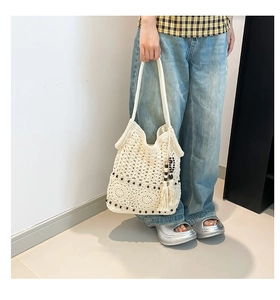 Detail of hand-woven crochet tote bag with fringe tassels and beads for beach use