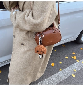 Close-up of brown vintage crossbody bag with plush dog charm and PANTOR SERIES text