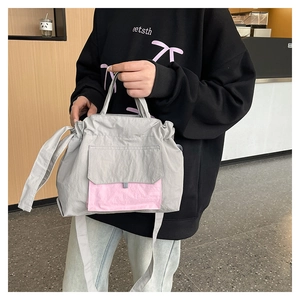 Détail du sac cabas en nylon gris avec poche rose contrastante et bandoulière réglable