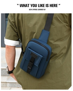Rear view of a man wearing a dark blue waterproof nylon crossbody bag in an outdoor setting
