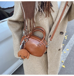Brown litchi grain handbag with teddy bear charm and silver hardware shown on cross body