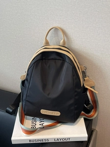 Minimalist black nylon backpack with khaki leather trim and striped shoulder strap