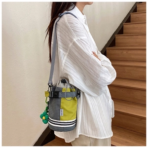 Detail of color-block checkered bicycle bucket bag with drawstring and sunflower charm