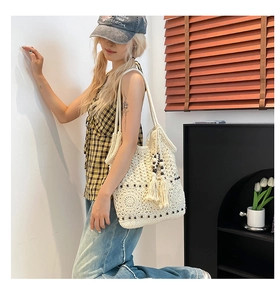 Detail of white crochet shoulder bag with hollow floral pattern and beaded tassels