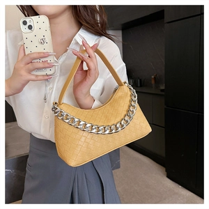 Close-up of a bright yellow woven hobo bag with bold silver metal chain and leather handle