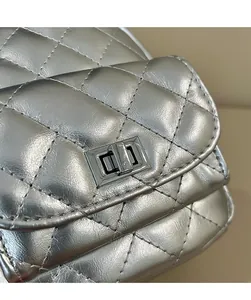 Detail of silver metallic quilted crossbody bag with rectangular rotating metal lock