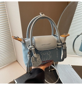 Detailed view of denim dumpling bag featuring puppy print and adjustable leather strap