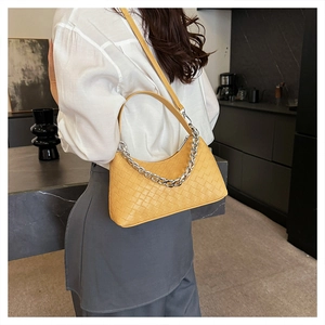Detail of yellow woven leather hobo bag with silver chain strap on model's shoulder