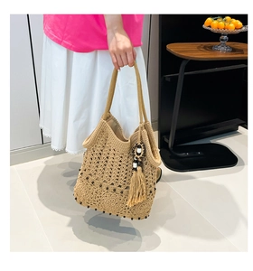 Detailed close-up of handmade woven tote bag with fringe tassel and black bead accents