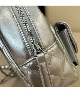 Detail of metal zipper and quilted rhombus texture on a silver crossbody bag