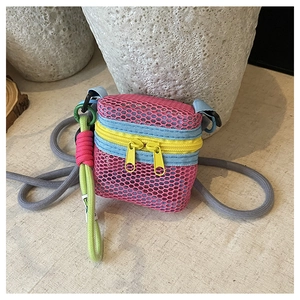 Macro detail of multi-colored mesh mini bag with double yellow zippers and rope strap