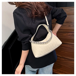 Detail view of cream woven underarm bag with decorative silver chain and leather strap