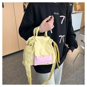 Vue détaillée du sac fourre-tout en nylon jaune avec poche avant rose et bandoulière