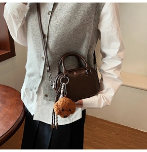 Detail of a brown vintage leather handbag with PANTOR logo and cute teddy bear charm