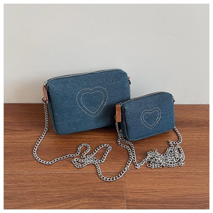 Detail view of denim chain bags set with stitched heart patterns and silver metallic straps