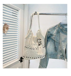 Detail of white crochet tote bag with hollow flower patterns and black bead accents