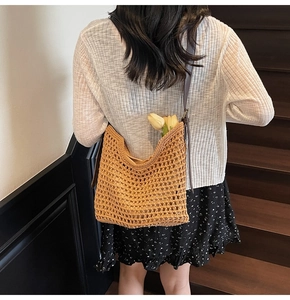 Detail of hand-woven cotton shoulder bag with hollow mesh texture and leather strap