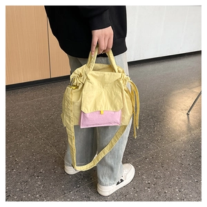 Détail du sac cabas en nylon jaune avec poche rose et cordon de serrage sur un mannequin