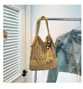 Detail of handmade crochet tote bag with circular flower patterns and tassel charm