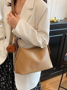 Sac bandoulière kaki minimaliste avec breloque ours et écharpe dans un décor intérieur