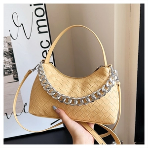 Detail of yellow woven leather bag featuring a chunky silver chain and adjustable strap