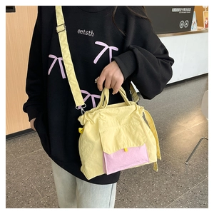 Détail d'un sac cabas en nylon jaune vif avec poche rose présenté dans un café moderne