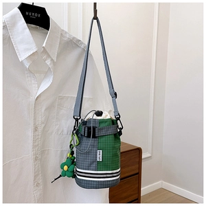 Detail of gray-green checkered drawstring bicycle bucket bag hanging on a hook