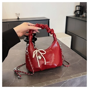 Detail of red pleated leather handbag with pearl bow and silver heart pendant