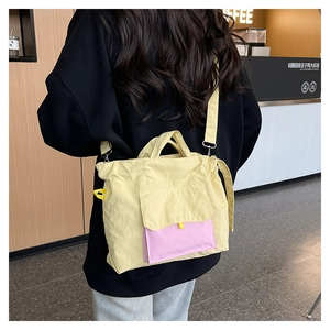 Détail du sac cabas en nylon jaune clair avec poche contrastée rose et boucles en métal