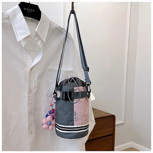 Detail showing checkered bicycle cylinder bag with drawstring and floral plush charm