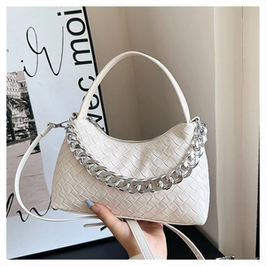 Close-up of white woven hobo bag with silver chain strap and leather handle details