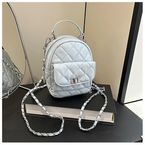 Close-up of light blue quilted mini backpack with silver chain strap and metal lock