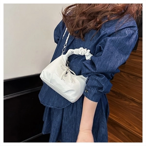 Detail of white glossy pleated hobo bag with pearl bow charm and delicate chain strap