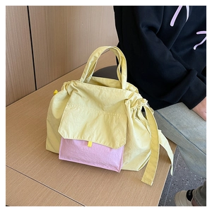 Détail d'un cabas en nylon jaune avec poche rose contrastante et fermeture à cordon