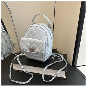 Detail of light blue quilted mini backpack featuring chain straps and a metal twist-lock