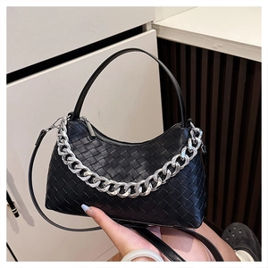 Detail of black woven leather handbag featuring a chunky silver chain and zip closure