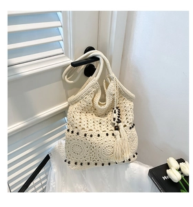 Detail of crochet weave pattern with dark wood beads and side tassel on off-white beach bag