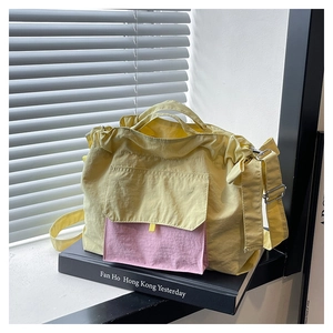 Détail d'un sac cabas en nylon jaune clair avec une poche contrastante rose à l'avant