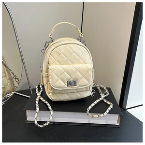 Detail of quilted diamond pattern and silver twist lock on creamy yellow mini bag