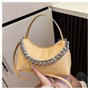 Close-up of woven beige hobo bag with chunky silver chain and leather shoulder strap