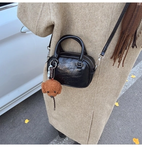 Chic black vintage satchel with cute teddy charm worn on beige wool winter coat